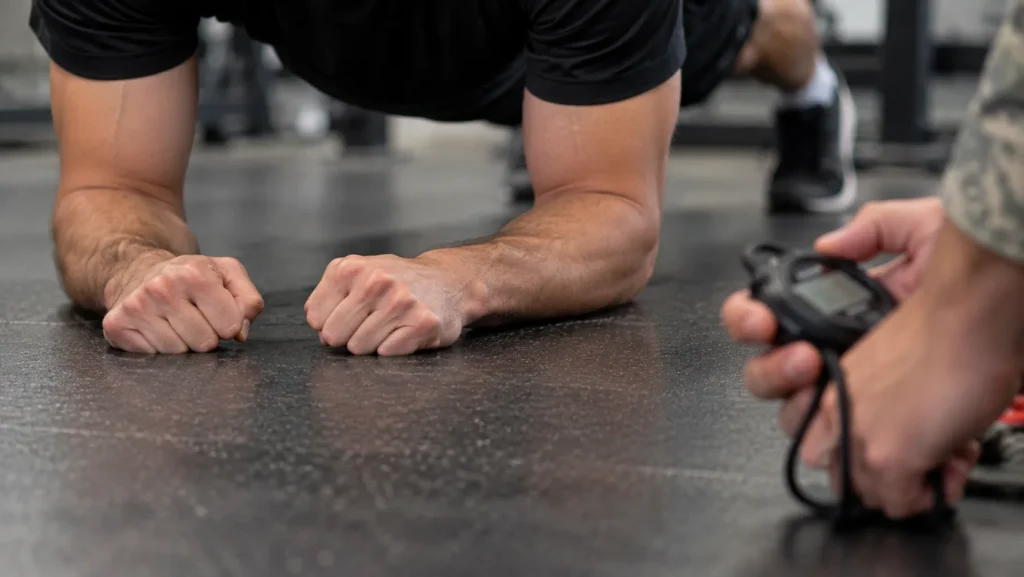Close view of a soldier's fists pinky-side down on the floor during a plank hold