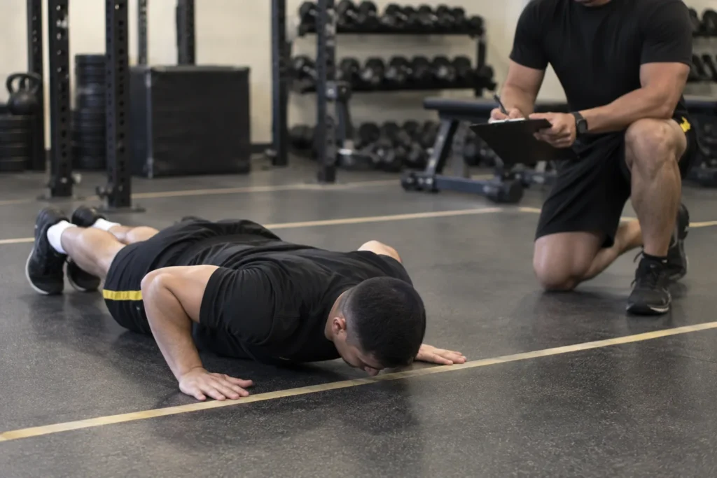 Soldier performing a hand-release push-up while a grader scores from a clipboard